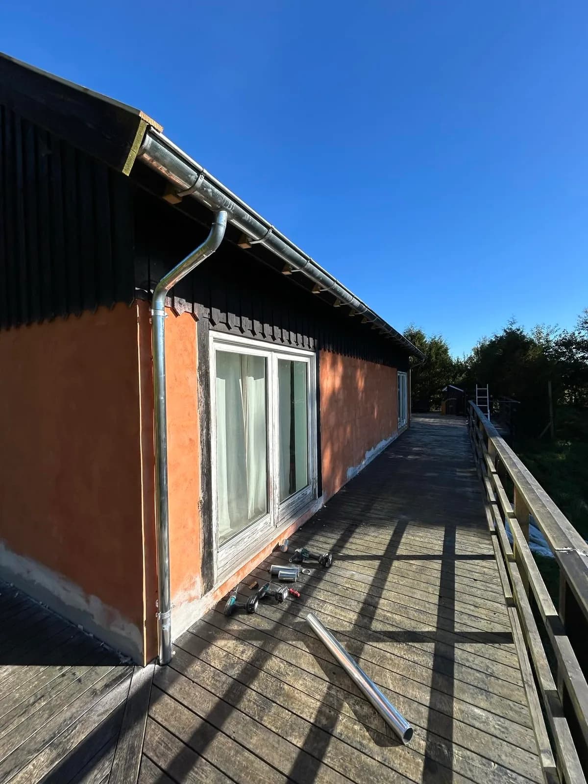 Ny tagrende og nedløbsrør langs et hus med terrasse