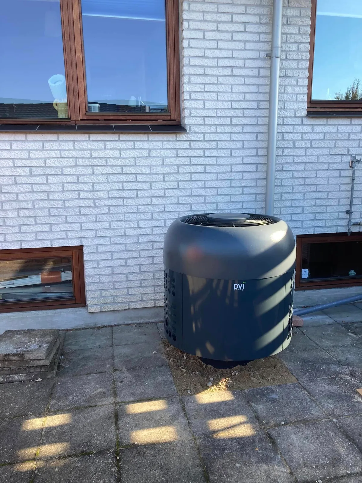 DVI-varmepumpens udedel ved en lys mur i Jyllinge