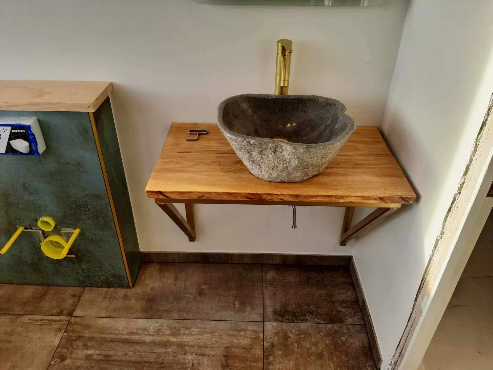 Rund håndvask på en træbordplade i et badeværelse under renovering